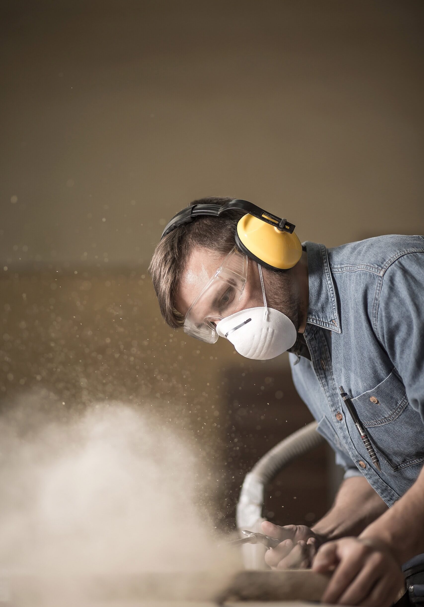 Carpenter wearing protective headphones while using electric saw